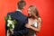 Young man hiding beautiful flowers for his beloved girlfriend behind back on color background