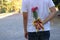 Young man hiding red roses behind his back for surprise his girlfriend in honor of Valentine`s day