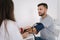 Young man with high blood pressure. Female doctor using sphygmomanometer with stethoscope checking blood pressure to a