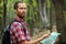 Young man hiking through forest and looking at the map