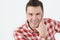 Young man in hipster shirt holding hand on chin and standing against white background