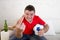 Young man holding ball watching football game on tv gesturing upset and crazy angry giving the finger