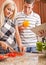 Young Man Holding Book Next to Woman Cooking