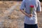 Young man is holding a bouquet of beautiful red roses in his back on countryside blurred background. Romance dating or Valenday`s