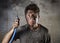 Young man holding cable smoking after electrical accident with dirty burnt face in funny sad expression