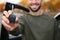 Young man holding car key near auto, closeup