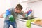 Young man holding cleaning detergent spray and sponge washing home kitchen clean angry in stress