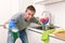 Young man holding cleaning detergent spray and sponge washing home kitchen clean angry in stress