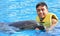 Young man holding dolphin in pool