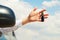 Young man holding keys remote from his car in hands over sky background