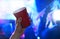 Young man holding red party cup in nightclub dance floor. Alcohol container in hand in disco. College student having fun.