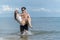 Young man holding young girlfriend and wading in ocean at the beach - sweet and funny lover couple