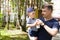 a young man holds a child in his arms, gives the baby a milkshake to drink. Father and son in the Park on a family vacation drink.