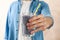 Young man holds glass berry milkshake against brown background