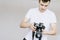 A young man holds a photo camera in his hand and looks at the photo on the photo camera. Isolated gray background