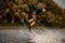 young man holds rope in his hand and skillfully jumping on wakeboard.