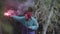 Young man holds up red smoke flare to signal for help in the middle of green wild nature. Stock footage. Hipster