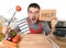 Young man at home kitchen in cook apron desperate in cooking stress