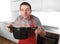 Young man at home kitchen in cook apron holding pot enjoying cooking smell