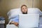 Young man in hospital room in bed using internet researching info on his own injury disease or sickness