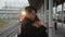 Young man is hugging woman standing at railway station outdoors. multiethnic