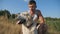 Young man hugs and strokes his labrador in meadow. Guy spends time together with his pet in nature. Love and friendship