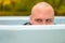 Young man hunkering down in an outdoor tub or pool