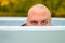 Young man hunkering down in an outdoor tub or pool