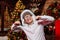 A young man in an Indian roach feather headdress and funny glasses poses and makes faces on a Christmas background