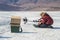 A young man inserts a fishing line into fishing rod during the winter ice fishing on the scenic Lake Baikal.