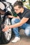 Young man inspecting a tire of a luxury car for insurance