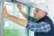 Young man installing blinds over window