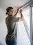 Young man installing curtains over window