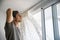 Young man installing curtains over window