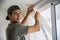 Young man installing curtains over window