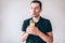 Young man isolated over background. Delightful happy guy drinking orange juice through plastic straw. Hold glass in