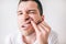 Young man isolated over white background. Close up portrait of irritated guy looking on camera and holding upper lip