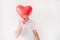 Young man isolated over white background. Guy hold red balloon in heart shape in front face. Cover or hide it. Love.