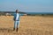 Young man in jeans, shirt, rubber boots in the field with his hands open, the concept of freedom, motivation, movement, front