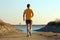 Young man jogging along seaside on sunny day, back view with Generative AI.