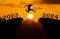 A young man jump between 2023 and 2024 years over the sun and through on the gap of hill silhouette evening colorful sky. happy ne