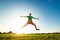 Young man jumping on meadow with dandelions