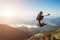 Young man jumping on top of a mountain against the sky