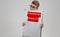 Young man keeps in front of him a poster with the financial penalty is on a light background