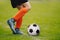 A young man kicking a football outdoors. Young football player training on a grass field