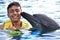 Young man kissing dolphin in pool