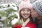 Young man kissing young woman in park in snow