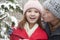 Young man kissing young woman in park in snow