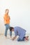 Young man is kneeling and reverently tying shoelaces to his domineering unidentified woman posing on a white background