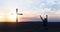 A young man kneels near the wooden cross of Jesus against the backdrop of the sunset. Repentance.